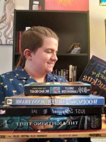 Evren the Nonbinary Knight reading a book with a stack of books in front of them