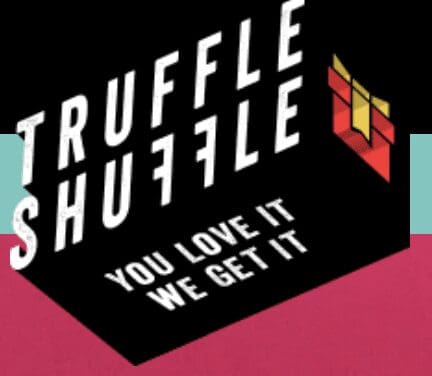 The image shows a logo for "Truffle Shuffle" with the text "TRUFFLE SHUFFLE" in bold, uppercase white letters slanted upward diagonally. Below the main text, the slogan "YOU LOVE IT WE GET IT" is written in smaller white text. To the right of the text, there is a stylized graphic resembling a three-dimensional cube with a yellow and red color scheme. The background is black, and the lower portion of the image features a solid maroon color.